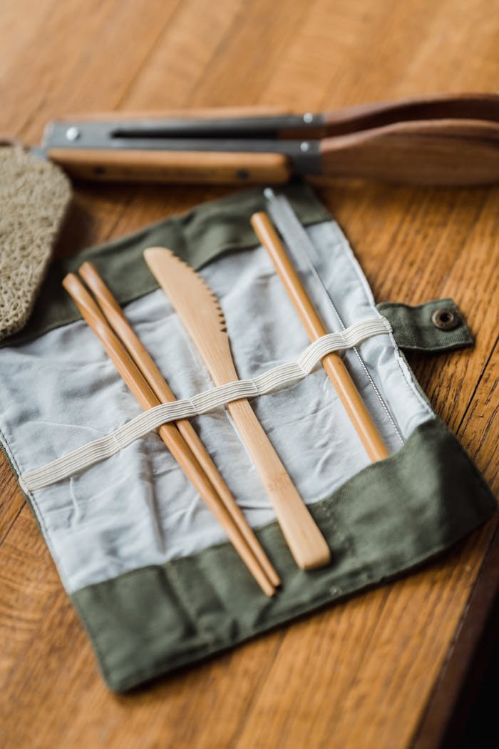 Bamboo cutlery kit with knife and chopsticks on a wooden table.
